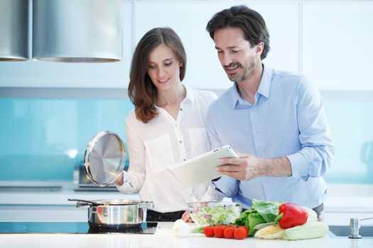 Portrait of a couple having a glass of red wine while cooking dinner