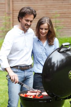 Happy couple cooking food on barbecue