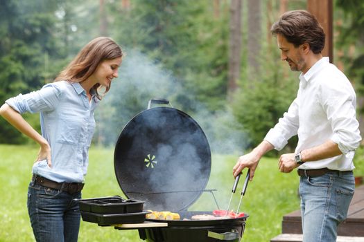 Happy couple cooking food on barbecue