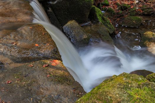 Top view beautiful waterfall flowing streams between stones and rocks, shot with a silky water effect.