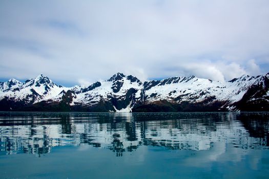 Landscape of mountains being reflected in the blue waters of Kenai Fjords near Seward, Alaska. 
