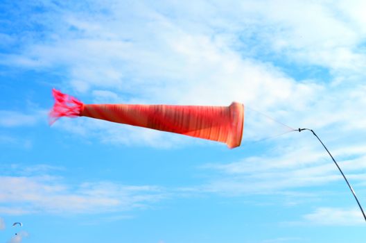 Windsock, used to determine the direction and speed of the wind, against the sky with a paraglider