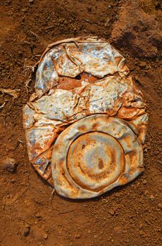 Old crushed rusty tin can on dusty background                               