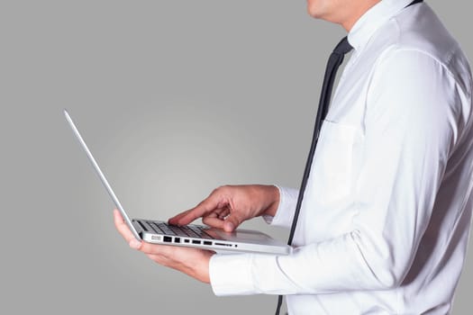 business man holding a laptop working on a gray background.