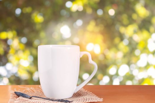 cup of hot coffee on wooden floor with bokeh background.