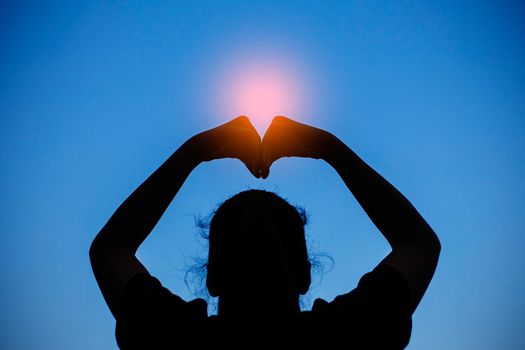 hands of woman with symbol of love on the sky.