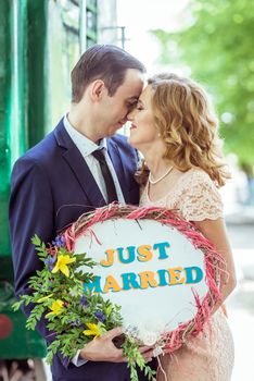 Close up portrait of loving couple. Man and woman standing near the wagon with a sign just married in Lviv Ukraine