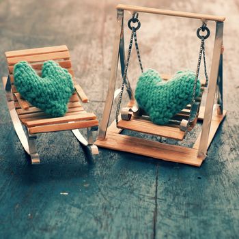 Two hearts be together, illustration for couple in love, take care and loving, green heart on handmade mini furniture as chair, swing, bed on wood background