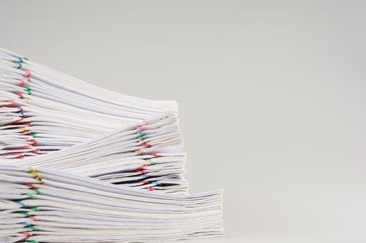 Pile overload of paperwork with colorful paper clip place on white background.