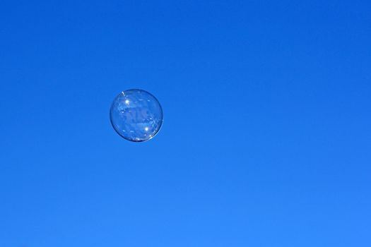 Soap bubble flying against the blue sky.