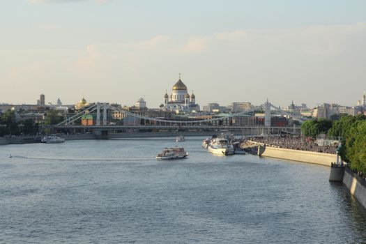 Moskva river with river buses from Novoandreevskiy Bridge. Krymsky bridge and Cathedral of Christ the Savior on the horizon in Moscow, Russia.