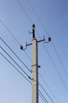 Concrete electric pole with wires against the sky