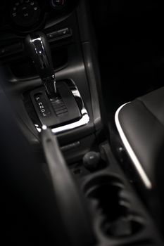 Modern Driving. Dark Vehicle Interior - Central Console with Cup Holders, Seats and Automatic Transmission Stick Shift. Vertical Photo. Vehicle Interiors Photo Collection