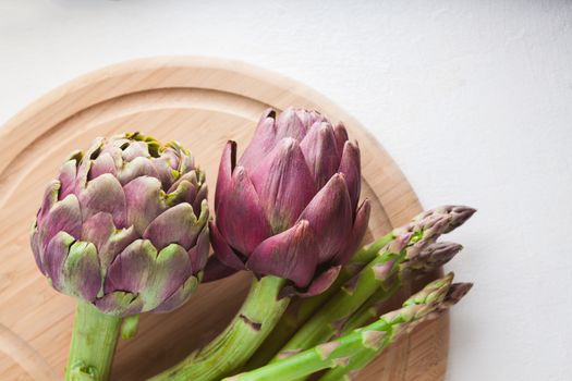 Artichokes and asparagus on a wooden board