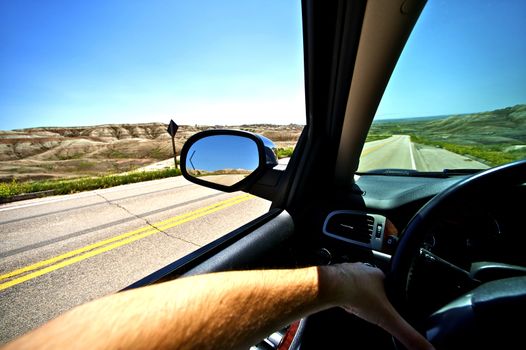 Driving Thru Summer. Summer Ride in Badlands. Wide Angle Photo Taken From Inside the Car. Male Hand on a Wheel. Transportation Photo Collection.
