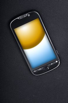 Smart Phone on Dark Carbon Background. Yellow-Blue Display Image. Modern Cellphone. Vertical Photo.