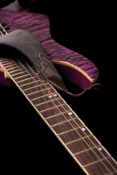 Purple Electric Guitar on Black Background. Part of the Guitar. Vertical Photo.
