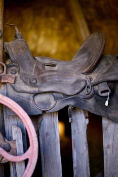 Saddle on a Wood Fence. Horse Seat on Wood Planks in Barn. Vertical Photo.