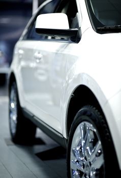 Side of the White Vehicle in Dealer Showroom. White SUV for Sale. Vertical Photo