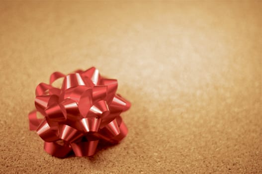 Small Burgundy Glossy Bow on the Cork Background. Bow Ornament.