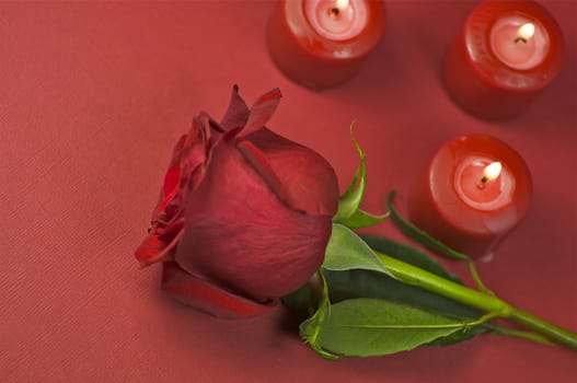 Red Rose and Three Burning Candles - Top View. Red Textured Paper Background