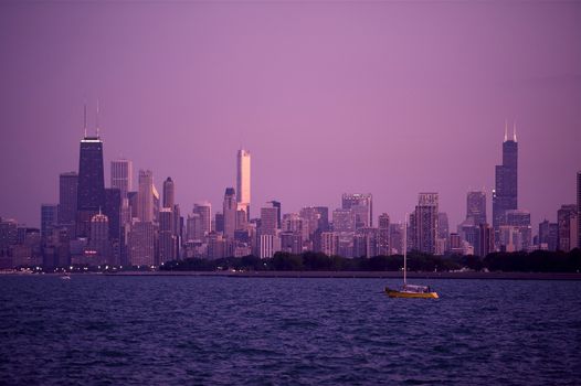 Chicago Skyline Panorama During Sunset. Beautiful Summer Evening in Chicago. Full Chicago Skyline with Small Boat on the Lake Michigan. Hancock Tower on the Left, Trump Tower in the Middle and Sears Tower on the Right Side of the Skyline.
