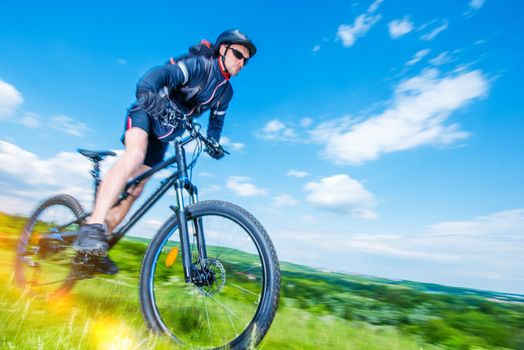Mountain Bike Rider. Summer Biking Trip. Speeding Caucasian Biker in Motion Blur.