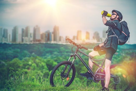 Mountain Biking Near the City. Mountain Biker Refreshing His Body By Drinking Fresh Cold Water.