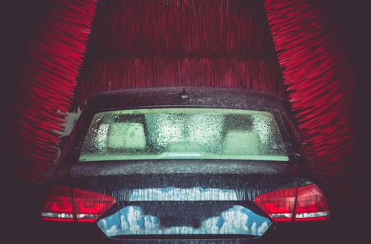 Automatic Brush Car Wash in Action. Elegant Modern Full Size Car in the Car Wash.