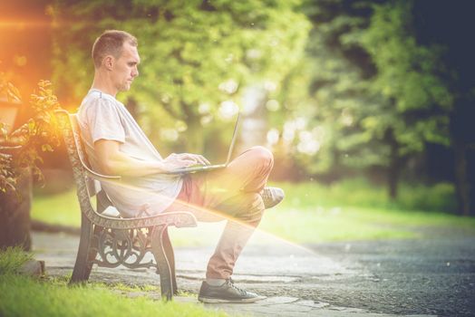 Outdoor Office Laptop Work. Men Working on His Laptop Computer in the Park During Sunny Summer Day. Outdoor Creativity