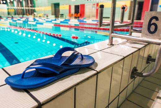 Swimming Pool Shoes on the Edge of the Pool. Swimming Concept Photo.