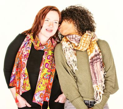 African American woman whispering into ear of friend wearing scarf