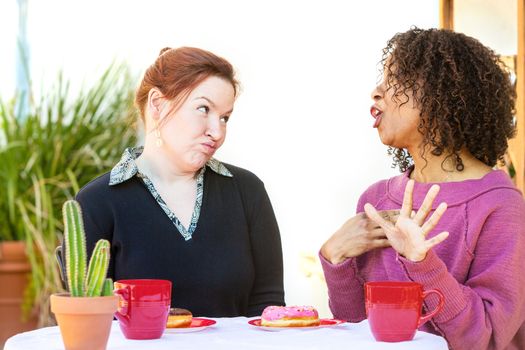 Woman with doubtful expression listening to friend talking at table
