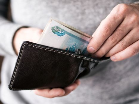 Hands take out russian rubles from wallet. Closeup on a man's hands as he is getting a banknote out of his wallet