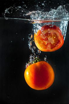 Tomatos splashing with in water.