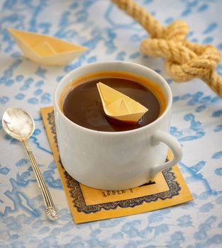 coffee cup and paper boat on map