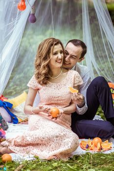 Smiling man and woman sitting on the ground and holdind a piece of orange in Lviv, Ukraine.