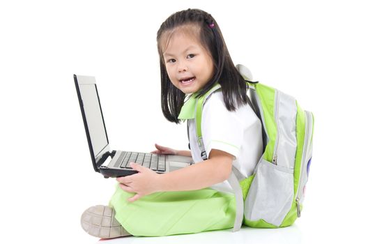 Happy little schoolgirl using laptop , isolated on white background