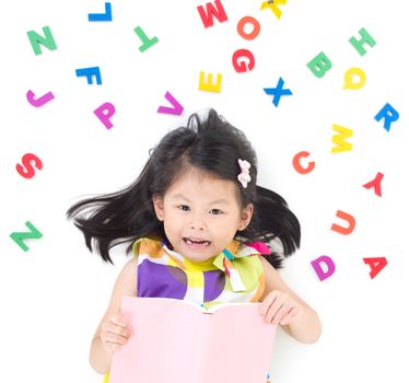 Lovely asian girl lying on the floor, holding a book, playing with Alphabets