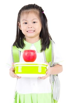 Asian primary school girl holding lunch box and apple. Healthy eating concept for schoolchild.