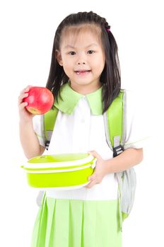 Asian primary school girl holding lunch box and apple. Healthy eating concept for schoolchild.