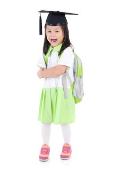 Asian primary student carried school bag and wearing mortarboard, isolated on white background
