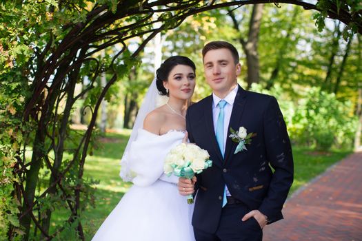 The bride tenderly embraced the groom standing under the green arch