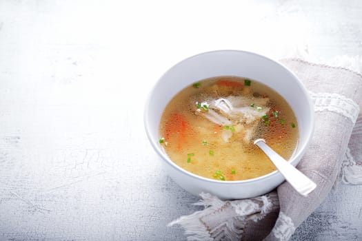 Homemade chicken soup with a spoon on a white napkin