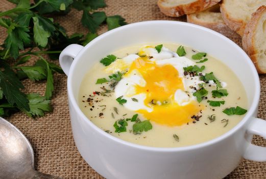 potato cream soup with bacon and poached eggs, herbs, spices