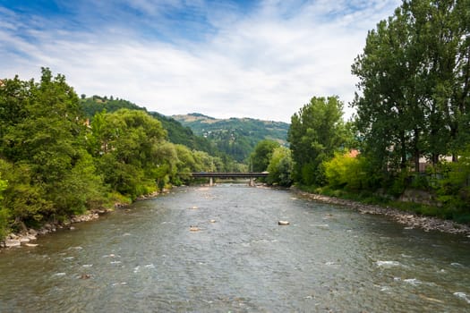 landscape with mountains trees and a bridge through river