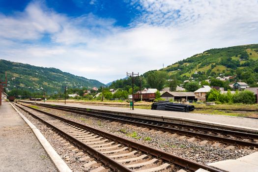 railroad of railway station in countryside which goes through the mountains under blue sky