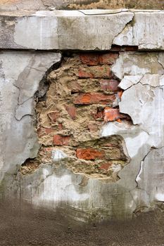 wall with cracks and fissures through which the brick is visible