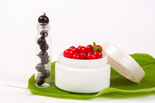 concept natural cosmetics made of redcurrant and black currant put on white background with green leafs