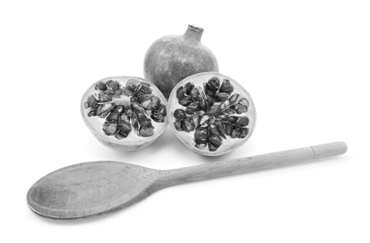 Whole pomegranate with two cut halves, with wooden spoon for removing seeds, isolated on a white background